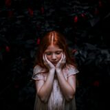 red haired girl standing near plant